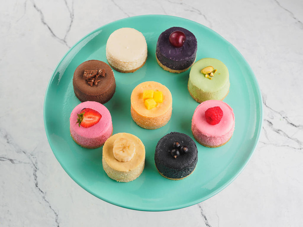 Round mini cheesecakes with fruits and berries on stand. - 写真・画像