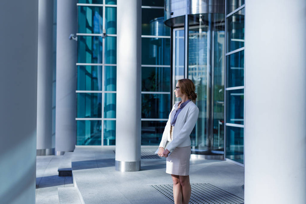 Pretty young woman standing in front of revolving door - Photo, Image