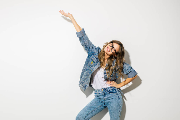trendy and retro. concept with young expressive and energic woman in jeans outfit presenting herself with joy on white background - Фото, изображение
