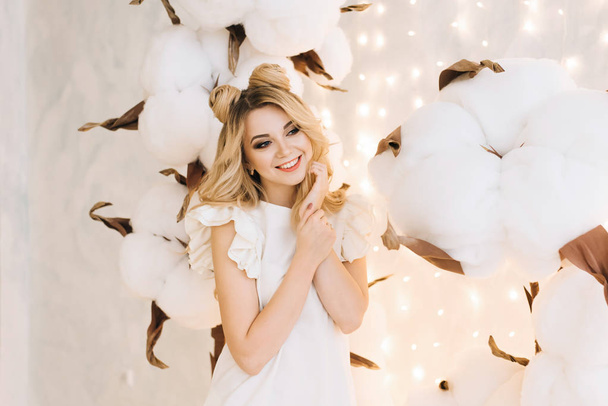 Christmas portrait of a beautiful girl with white hair. An attractive woman among the large branches of the cotton - Foto, Imagem