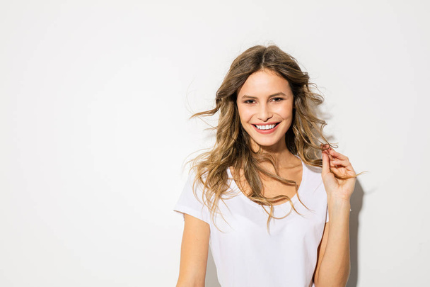 portrait of young and beautiful woman, expressive face, in white shirt smiling to camera - Foto, Imagen