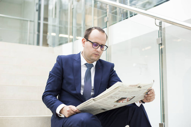 Portrait of a young handsome businessman reading a newspaper - Fotografie, Obrázek