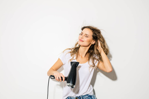 young attractive woman blowing her hair with hair dryer on white background - Photo, image