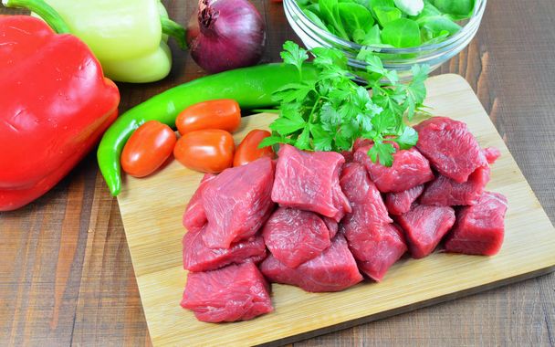 Cubi di carne, maiale crudo, manzo, vitello su tavola con verdure e ingredienti per cucinare gulasch o stufato
 - Foto, immagini