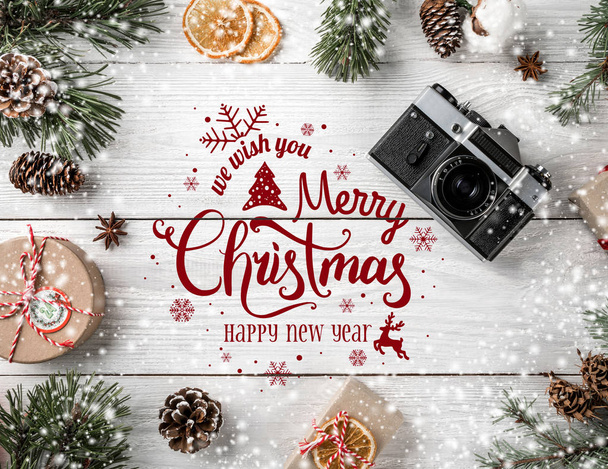Kerstmis en Nieuwjaar typografische op witte houten achtergrond met Fir takken, geschenken, camera. Xmas en gelukkig Nieuwjaar thema, sneeuw. Plat lag, top uitzicht - Foto, afbeelding