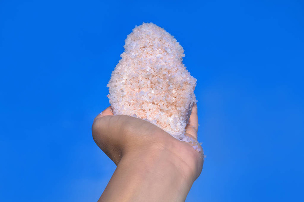 Pink salt crystals in hands from Sivash lake. Spa, medicine dermatology background. - Photo, Image