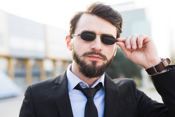 Portrait de hipster barbu avec des lunettes de soleil habillé en costume
. - Photo, image