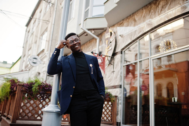 Amazingly looking african american man wear at blue blazer with brooch, black turtleneck and glasses posed at street. Fashionable black guy. - Foto, imagen