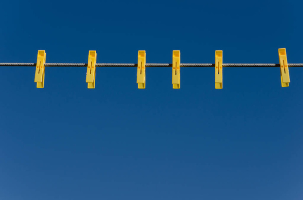 Yellow clothespins on a blue sky background - Photo, Image