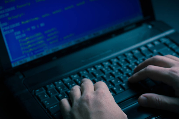 Internetes hacker tolvaj koncepció. Hacker használ laptop, számítástechnikai berendezések támadni. Sötét és félelmetes világítás. Egy csomó jelképek a számítógép képernyőjén. Szelektív összpontosít. - Fotó, kép