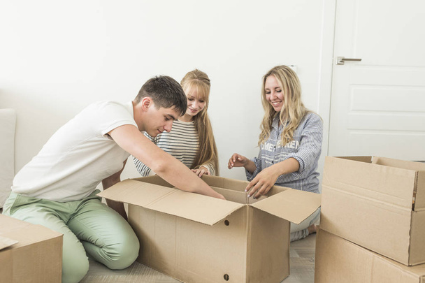 Family unpacking cardboard boxes at new home. moving to a new house. concept of a happy family and housewarming - Foto, afbeelding