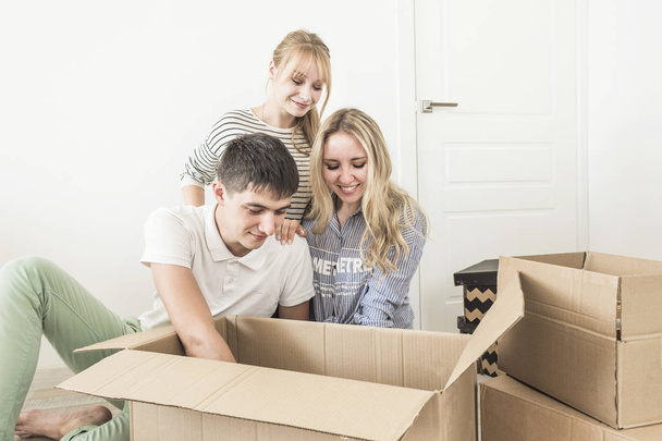 Family unpacking cardboard boxes at new home. moving to a new house. concept of a happy family and housewarming - Zdjęcie, obraz