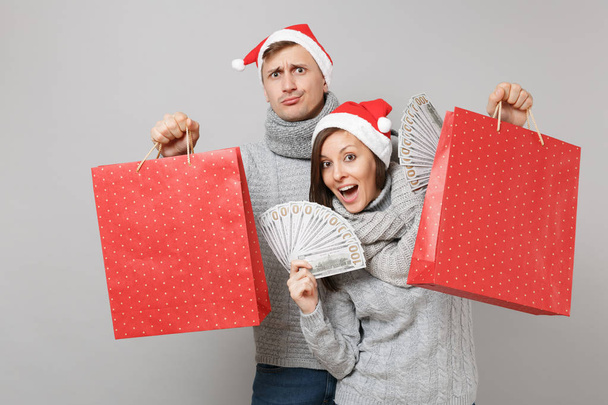 陽気な楽しいカップル女の子男赤灰色の壁の背景、スタジオ ポートレートに分離されたサンタのクリスマス ハット グレー セーター スカーフで。幸せな新しい年 2019年お祝いの休日党の概念。コピー スペースをモックアップします。 - 写真・画像