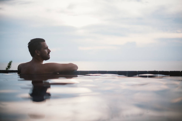 Portrait d'un jeune homme beau dans une piscine extérieure. Attrayant gars avec une barbe sur le côté de la piscine
 - Photo, image