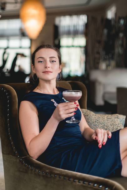 Fille magnifique à la mode dans une robe bleu foncé cocktail à boire dans un bar de luxe lobby de l'hôtel
 - Photo, image