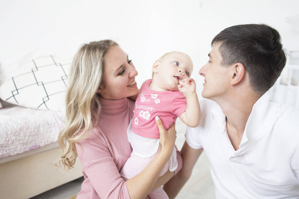 Smiling happy young mother and father standing in their living room at home affectionately cradling the cute baby girl in their arms - Zdjęcie, obraz