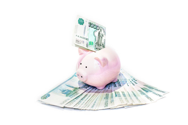 Pink piggy bank with a banknote inserted in the slot in a financial planning, savings and investment concept - Фото, зображення