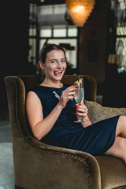 Fille magnifique à la mode dans une robe bleu foncé cocktail à boire dans un bar de luxe lobby de l'hôtel
 - Photo, image