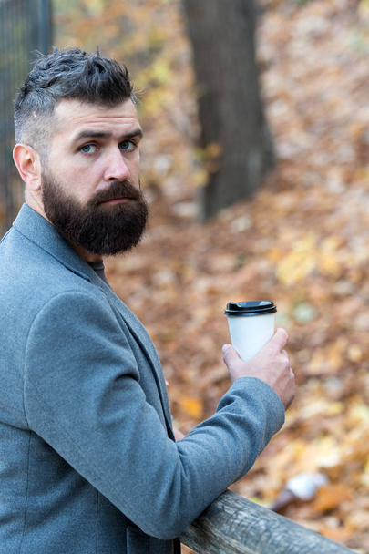 Drink it on the go. Man bearded hipster prefer coffee take away. Businessman bearded guy drink coffee outdoors. Hipster hold paper coffee cup and enjoy park environment. Relaxing coffee break - Фото, зображення