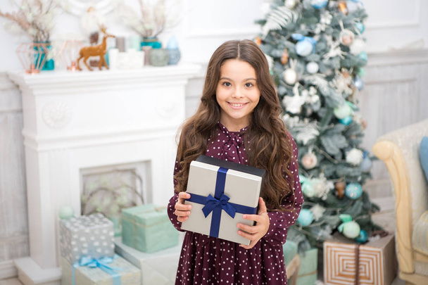 Christmas is coming. Small cute girl received holiday gift. Best christmas gifts. Child excited about unpacking her gift. Kid little girl in elegant dress and gift box christmas tree background - Φωτογραφία, εικόνα