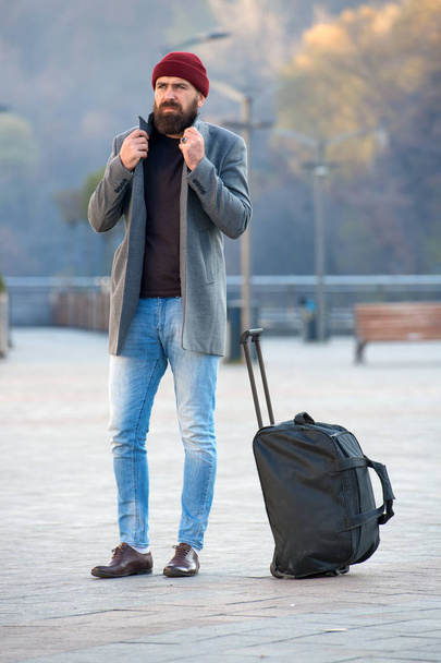Wohnungssuche. Ein bärtiger Hipster mit großer Gepäcktasche wartet darauf, dass ihn ein Taxi ins Hotel bringt. Reisetipps. Reisende mit Koffer erreichen Reiseziel. Hipster reiselustig - Foto, Bild