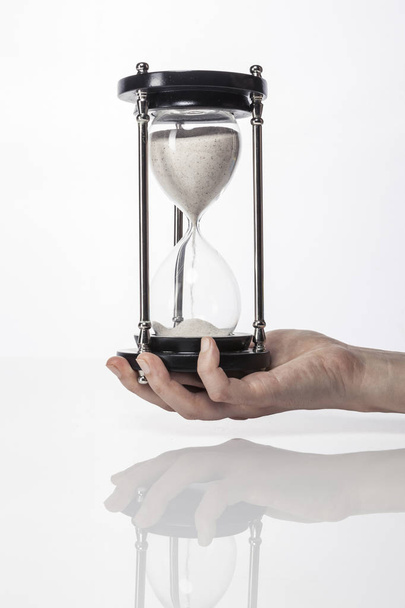 woman(female) hand hold a vintage sand timer isolated white. - Foto, Imagem