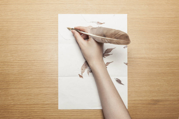 Frauenhand hält einen Stift mit Buchstaben auf dem Holztisch. - Foto, Bild