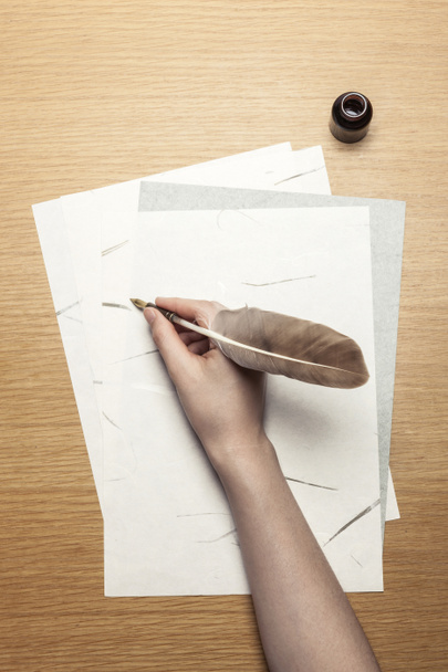 жінка рука тримає ручку з буквою на дерев'яному столі
. - Фото, зображення