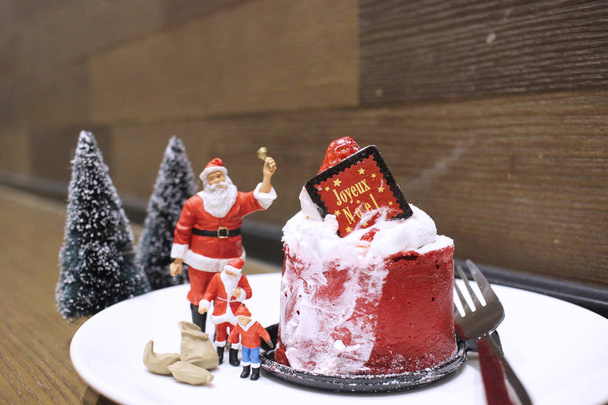 de kleine afbeelding van de kerstman met kerst cake - Foto, afbeelding