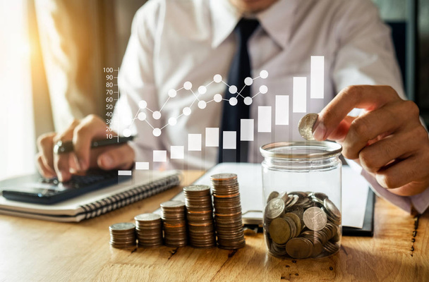 бізнесмен тримає монети в склі з використанням смартфона і калькулятора для розрахунку концепції економії грошей для фінансового обліку
 - Фото, зображення