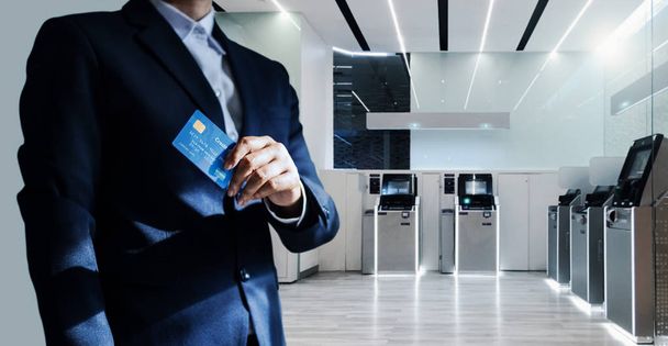 Bank manager and credit card in hand, business man standing confidently with pride in financial modern, futuristic, technology and banking network connection  - Photo, Image