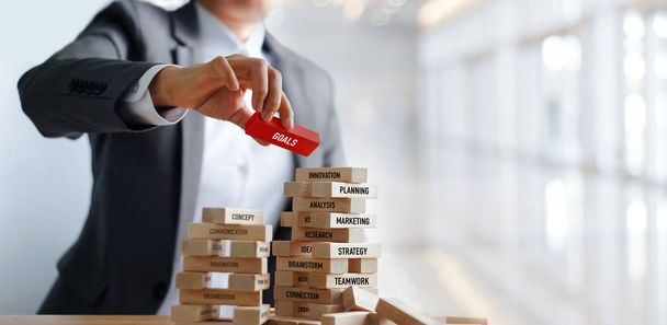 Businessman hand holding GOALS word on wooden blocks. Financial business. Marketing and strategy concept - Photo, image