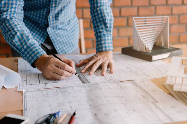 Engineering or architect reviewing blueprints and holding pencil on desk at home office. - Photo, Image
