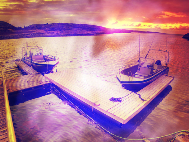 Barco de pesca con cañas de pescar flotando en la orilla, mar colorido noche. Filtro Hipster
.  - Foto, imagen
