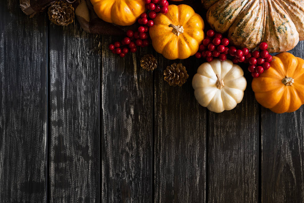 Vista superior de las hojas de arce de otoño con calabaza, manzana, maíz y bayas rojas sobre fondo de madera vieja. Concepto del día de Acción de Gracias
. - Foto, imagen