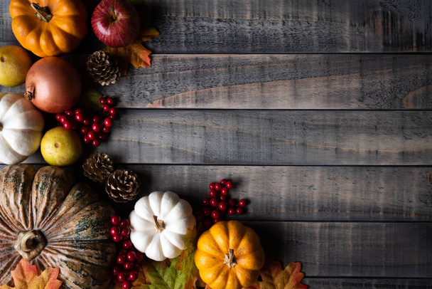 Κάτοψη του σφενδάμνου φθινόπωρο φύλλα με κολοκύθι, μήλο, καλαμπόκι και κόκκινα μούρα σε παλιό ξύλινο υπόβαθρο. Ημέρα των Ευχαριστιών έννοια. - Φωτογραφία, εικόνα