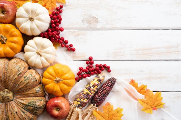Ansicht von Herbst-Ahornblättern mit Kürbis und roten Beeren auf weißem Holzhintergrund. Konzept zum Erntedankfest. - Foto, Bild