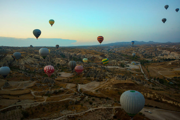 GOREME, TURKEY: Colorful Hot air balloons fly over Cappadocia, Goreme, Central Anatolia, Turkey. Hot-air ballooning is very popular tourist activity in Cappadocia.Balloon flight at dawn, beautiful view of the mountains and balls. - Foto, imagen