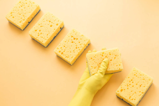 Flat lay Detergentes y accesorios de limpieza y manos de mujer en guantes de goma en color amarillo. Servicio de limpieza concepto. Pisos, Vista superior
. - Foto, Imagen