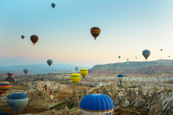 GOREME, TURKEY: Colorful Hot air balloons fly over Cappadocia, Goreme, Central Anatolia, Turkey. Hot-air ballooning is very popular tourist activity in Cappadocia.Balloon flight at dawn, beautiful view of the mountains and balls. - Foto, afbeelding