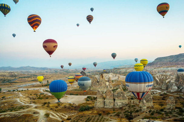 GOREME, TURKEY: Colorful Hot air balloons fly over Cappadocia, Goreme, Central Anatolia, Turkey. Hot-air ballooning is very popular tourist activity in Cappadocia.Balloon flight at dawn, beautiful view of the mountains and balls. - Фото, изображение