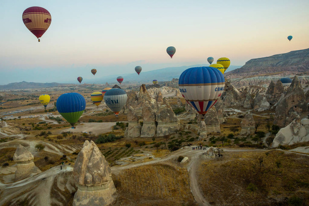 GOREME, TURKEY: Colorful Hot air balloons fly over Cappadocia, Goreme, Central Anatolia, Turkey. Hot-air ballooning is very popular tourist activity in Cappadocia.Balloon flight at dawn, beautiful view of the mountains and balls. - Φωτογραφία, εικόνα