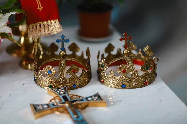 Arany koronák és jegygyűrűk az oltárnál az esküvői pár templomában. hagyományos vallási esküvő. - Fotó, kép