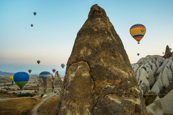 Monet värikkäät kuumailmapallot lentävät vuorten yläpuolella - Cappadocia-panoraama auringonnousun aikaan. Laaja maisema Goreme laaksossa Cappadocia - mainostaulu tausta matkakonsepti Turkissa
. - Valokuva, kuva