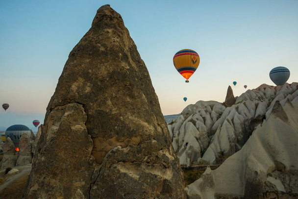 Many colorful hot air balloons flight above mountains - panorama of Cappadocia at sunrise. Wide landscape of Goreme valley in Cappadocia - billboard background for your travel concept in Turkey. - Valokuva, kuva