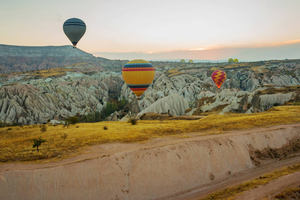 Many colorful hot air balloons flight above mountains - panorama of Cappadocia at sunrise. Wide landscape of Goreme valley in Cappadocia - billboard background for your travel concept in Turkey. - Фото, изображение