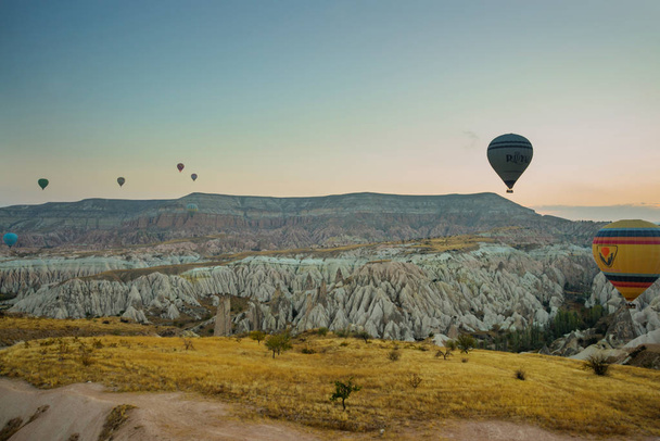 Many colorful hot air balloons flight above mountains - panorama of Cappadocia at sunrise. Wide landscape of Goreme valley in Cappadocia - billboard background for your travel concept in Turkey. - Foto, Bild