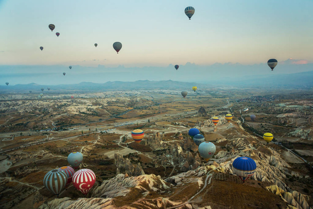 Many colorful hot air balloons flight above mountains - panorama of Cappadocia at sunrise. Wide landscape of Goreme valley in Cappadocia - billboard background for your travel concept in Turkey. - Foto, afbeelding