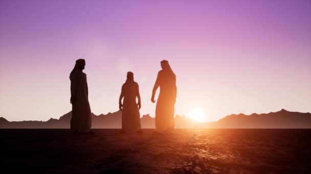 die Silhouetten von drei arabs in dishdasha sprechen miteinander. schöne Morgendämmerung - Filmmaterial, Video