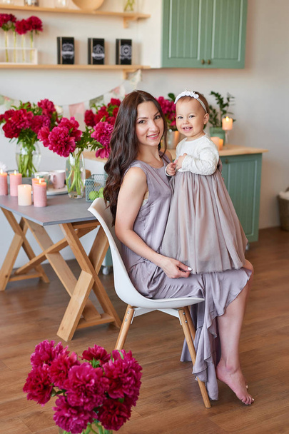 anya és lánya, elegáns ruhák, konyha, díszített pünkösdi rózsa - Fotó, kép